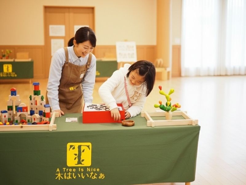 笑顔のおもちゃコンサルタントが、相談者に木のおもちゃを説明している様子