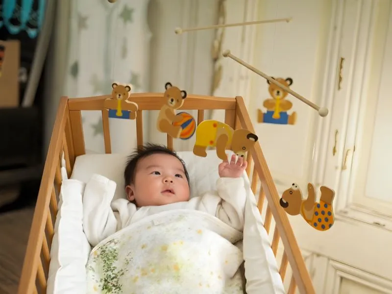 モビールを見つめる0歳赤ちゃん 視覚の発達を促す木のおもちゃ